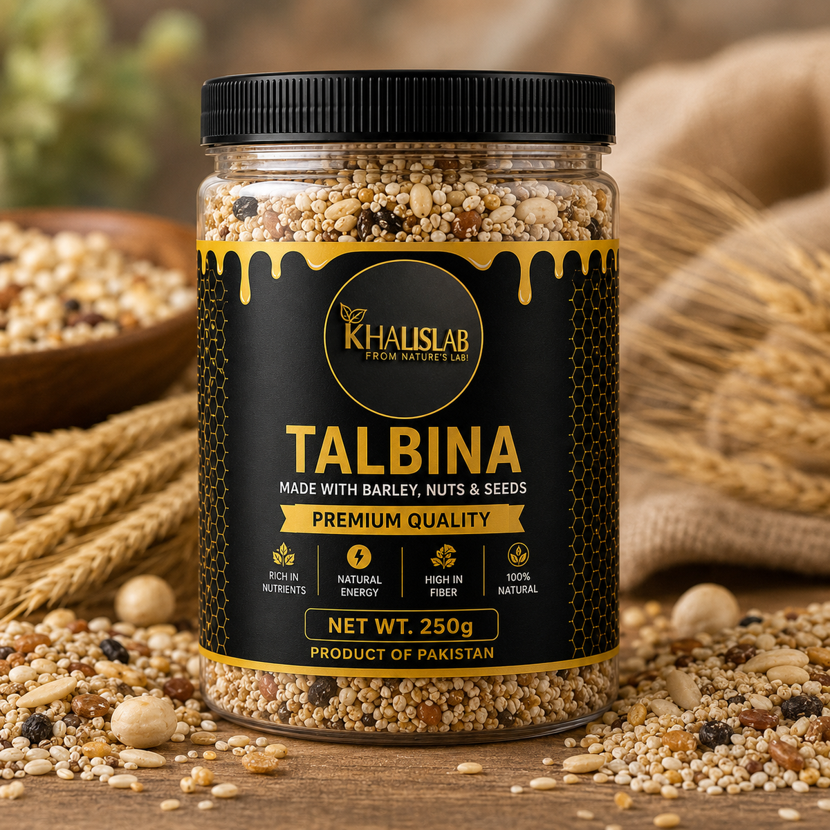 A jar of Khalislab Talbina flour, shown on a rustic wooden table surrounded by scattered grains, wheat stalks, and a burlap sack. The product is a clear jar with a black lid and a black label featuring gold text and honey-drip graphics.